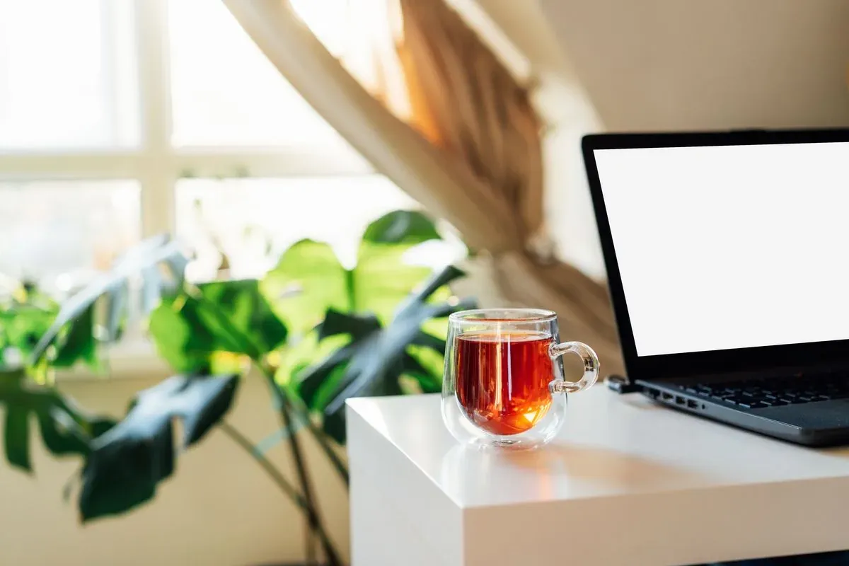 Méditation de groupe en ligne : une tasse de thé à côté d’un ordinateur portable ouvert