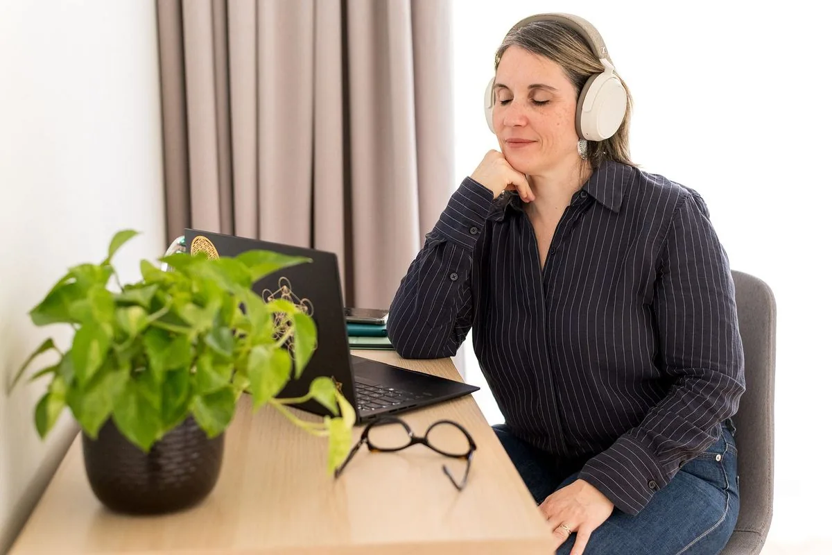 Méditation des chakras : Sophie médite les yeux fermés, un casque sur les oreilles, assise à son bureau