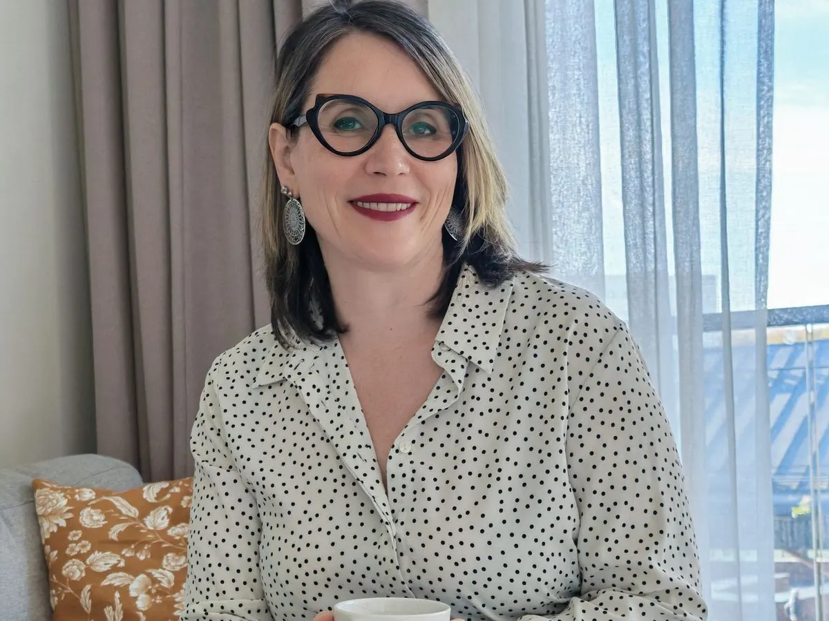 Méditation des chakras : Sophie Bordes-Meunier sourit, assise sur son canapé, une tasse entre les mains