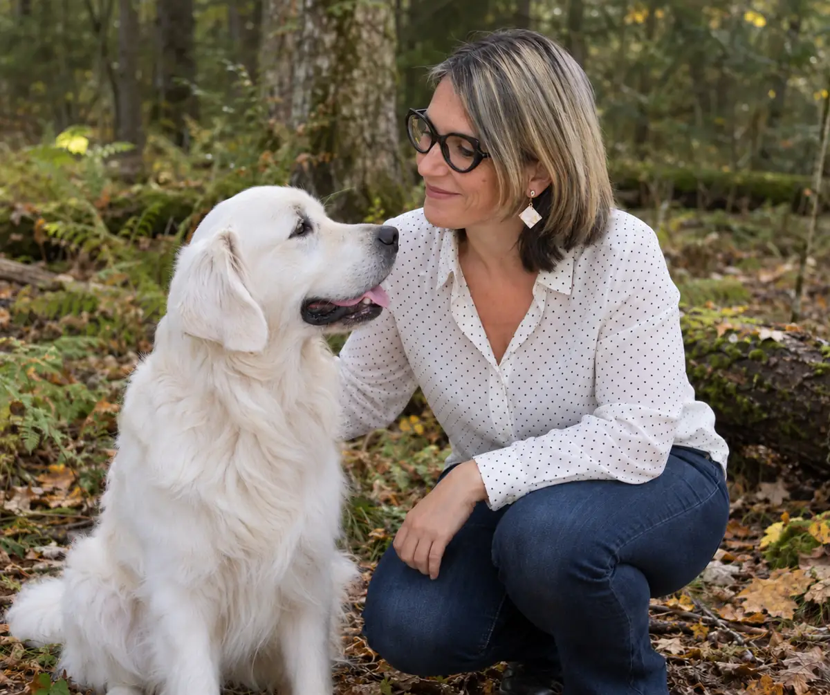 Soin énergétique animal : Sophie accroupie en forêt, face à Simba, un golden retriever blanc